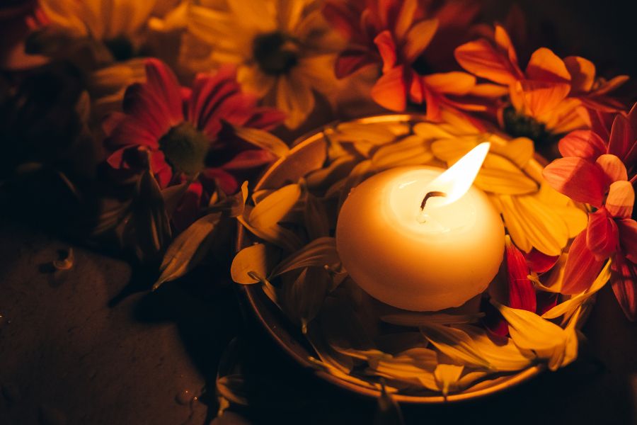 candle in dish surrounded by flowers and petals